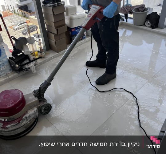 עובד ניקיון מפעיל מכונת קרצוף ופוליש על ריצוף גרניט פורצלן